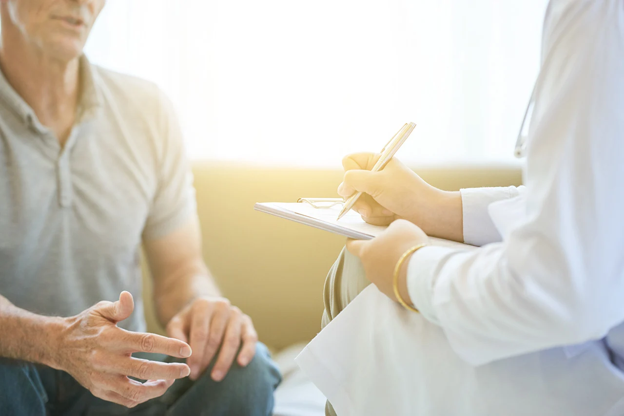 Doctor taking notes during patient consultation.